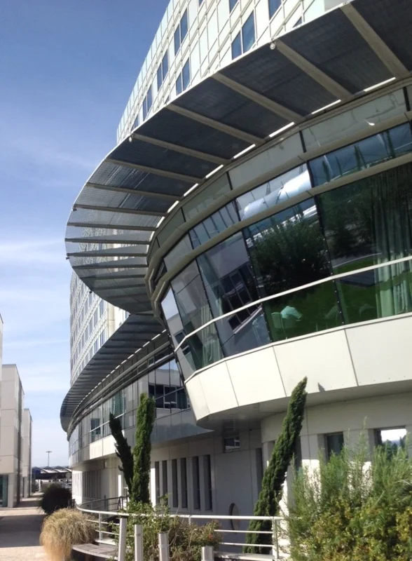 Press locked grating sun breaker with custom cut shape to conform to the building's architecture