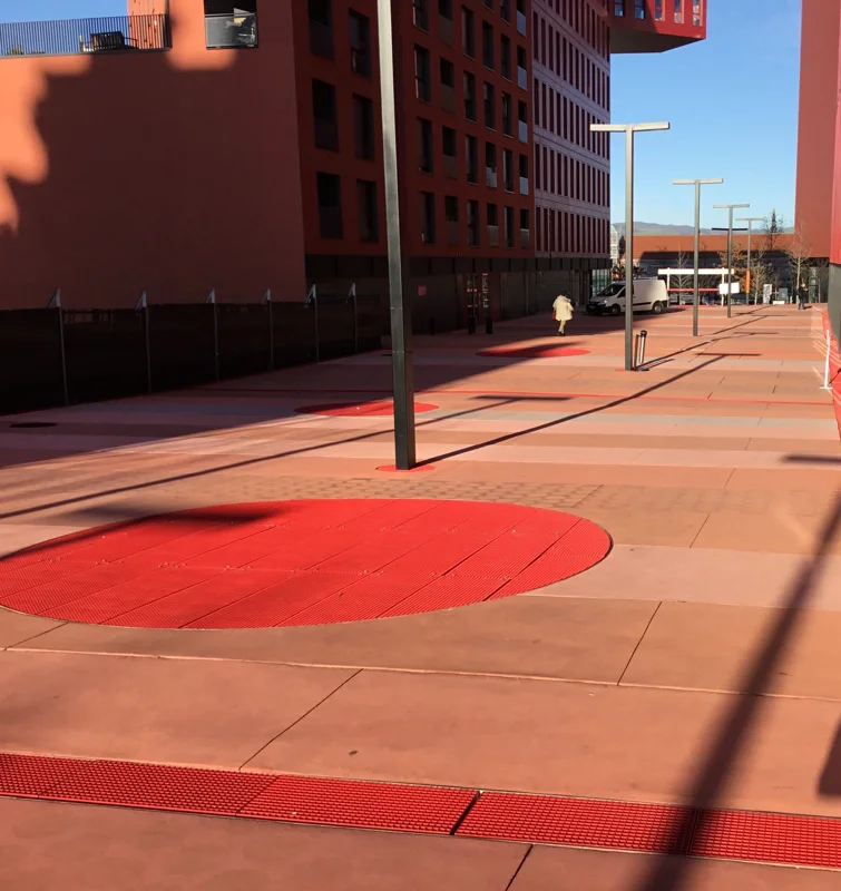 Pedestrian pathway on a railway station forecourt made with red powder-coated press locked grating