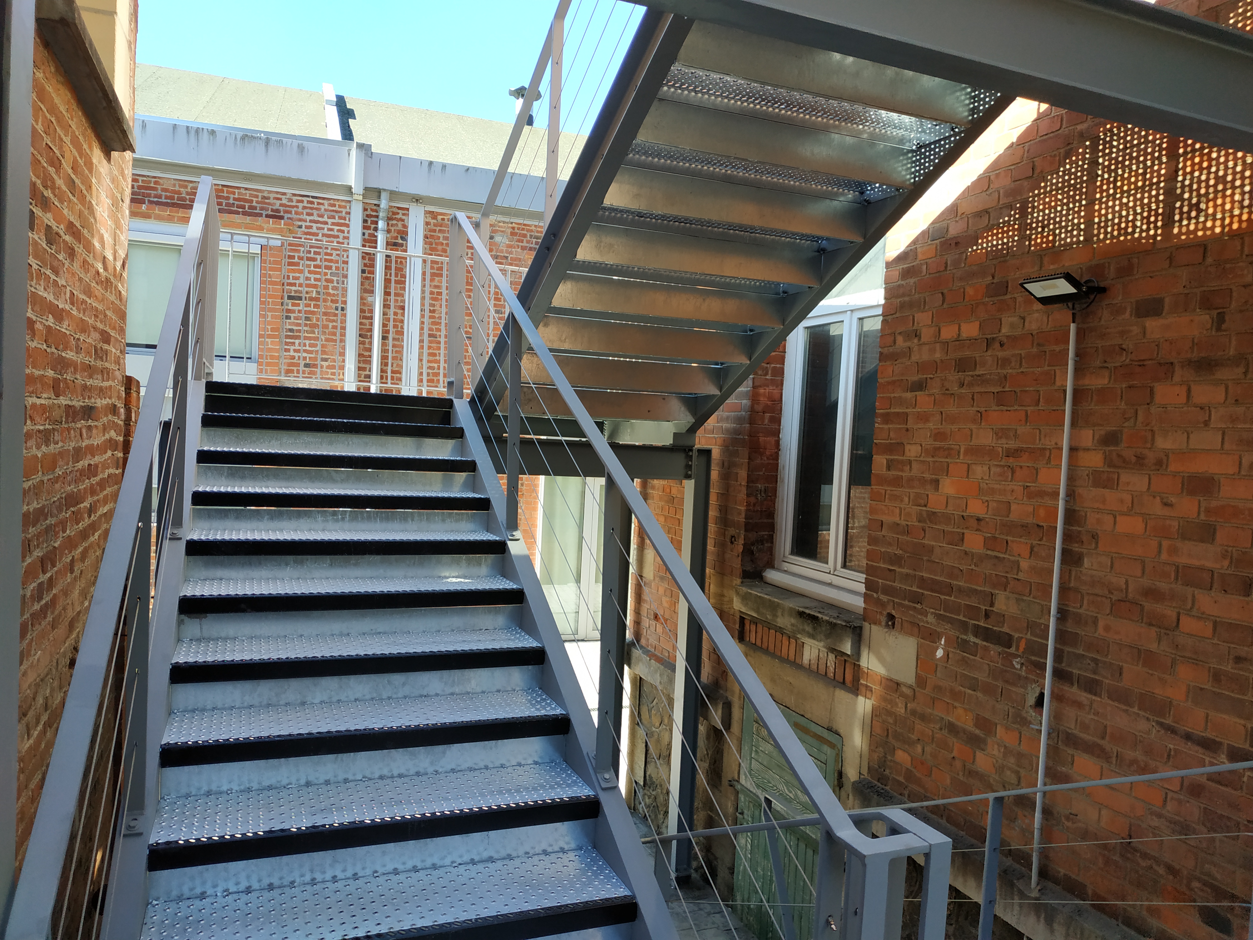 Escalier avec marches en grille PS-PMR avec nez peint et contremarche.