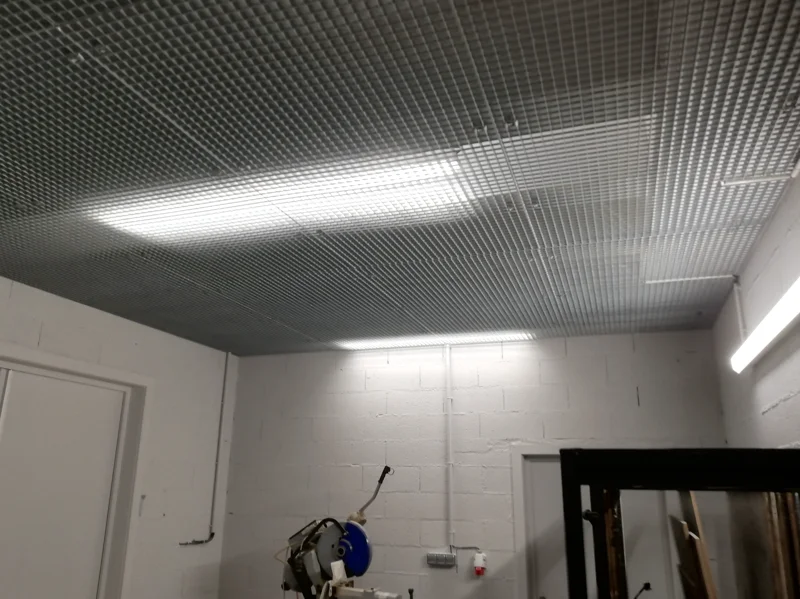 Faux plafond réalisé en caillebotis métallique permettant de dissimuler les évacuations, le chauffage