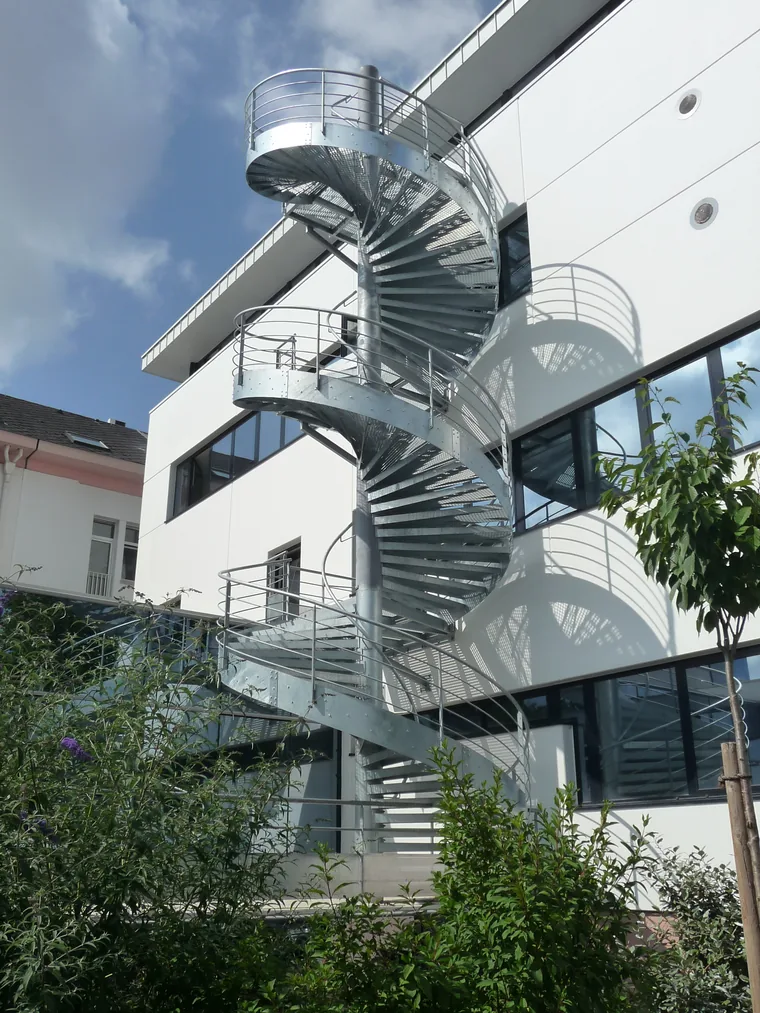 escalier hélicoïdal galvanisé avec marches en caillebotis sur la façade d'un bâtiment