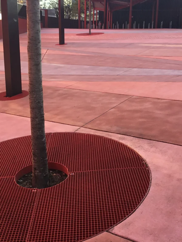 Grille d’arbres en caillebotis pressé avec forme de découpe et thermolaquage rouge sur le parvis rénové d’une commune