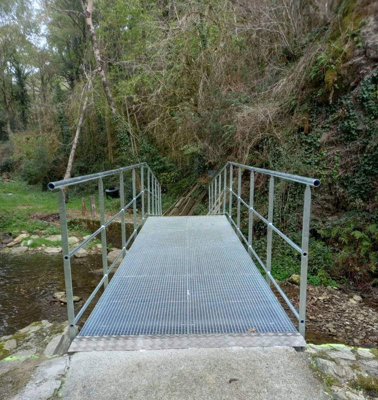 Passerelle piétonne en caillebotis pressé permettant au grand public de traverser une rivière
