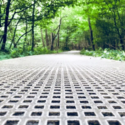 référence réalisation caillebotis en résine gris posé dans une forêt pour assurer un cheminement piéton
